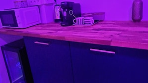 A kitchen with a microwave, coffee maker, and mug on the counter. - Suite romantique & Jacuzzi-Arles center (Arles)