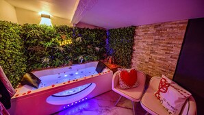 A spa area with a hot tub, two chairs, and a wall with greenery. - Suite romantique & Jacuzzi-Arles center (Arles)