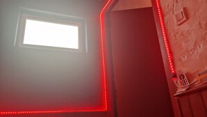 A room with a window, a red LED light strip, and a wall-mounted thermostat. - Suite romantique & Jacuzzi-Arles center (Arles)
