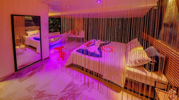 A modern bedroom with a bed, bedside tables, and a large mirror. - Suite romantique & Jacuzzi-Arles center (Arles)