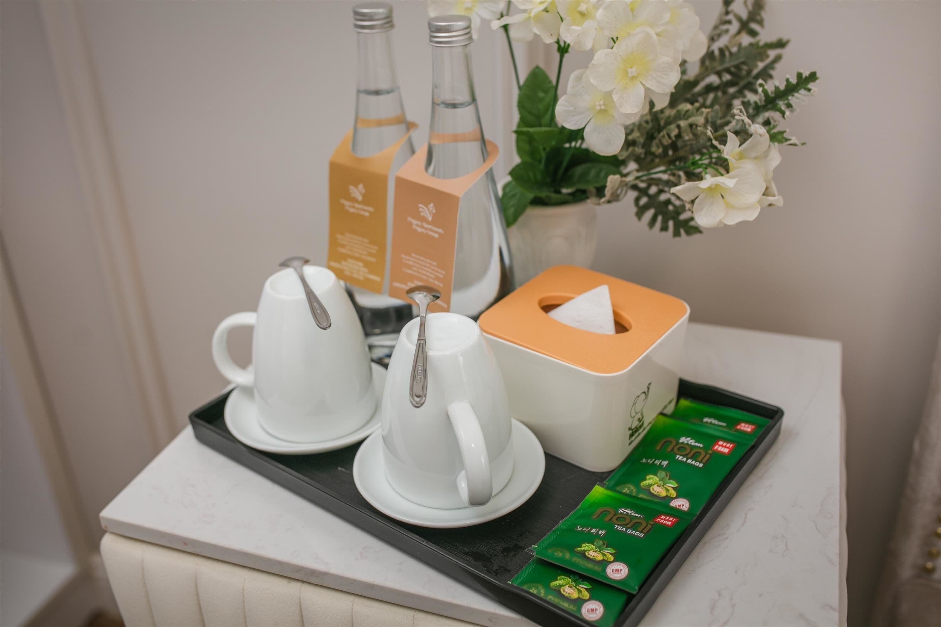 A tray with tea bags, a teapot, and a teacup set on a table.
