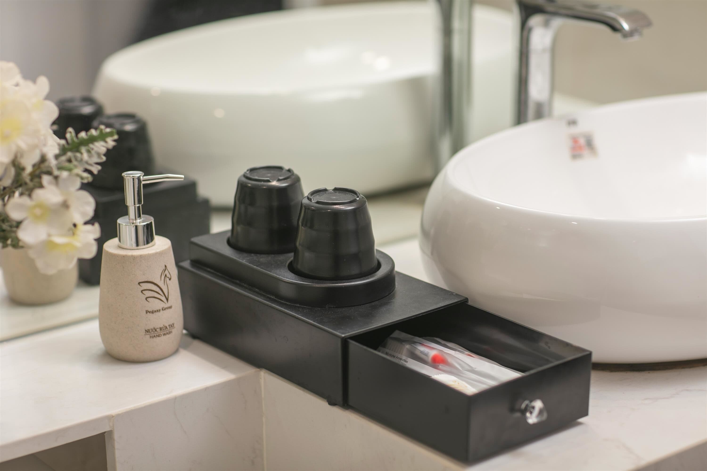 Une salle de bain avec un lavabo blanc, un distributeur de savon noir et un porte-savon noir.