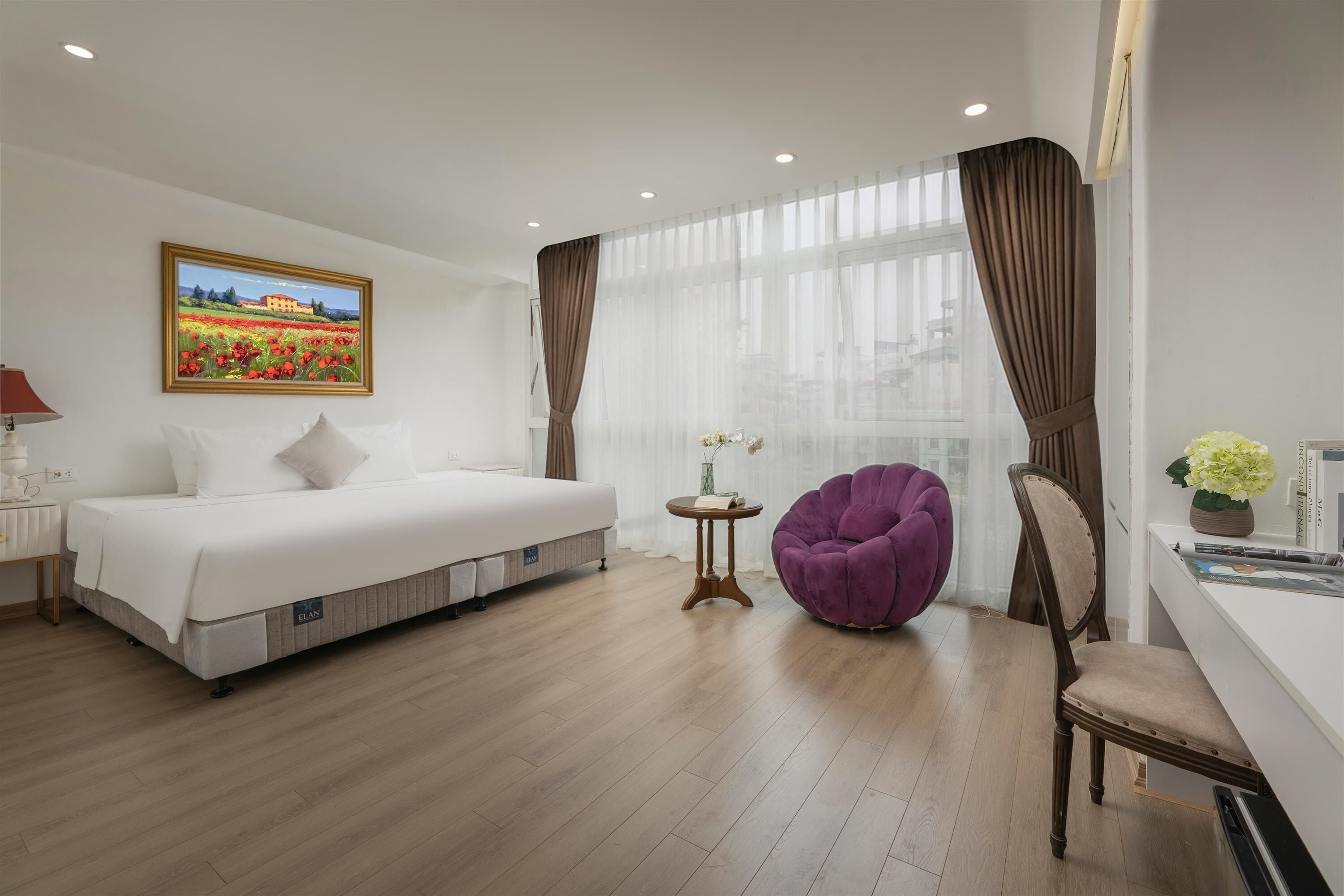 Une chambre d’hôtel avec un lit, une chaise violette, une petite table et un tableau accroché au mur.