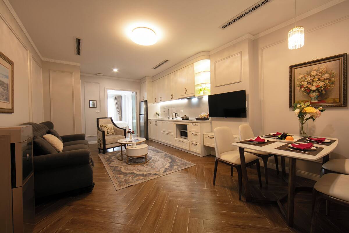 Una sala de estar moderna con un sofá, una mesa de centro y un comedor con una mesa preparada para cuatro.