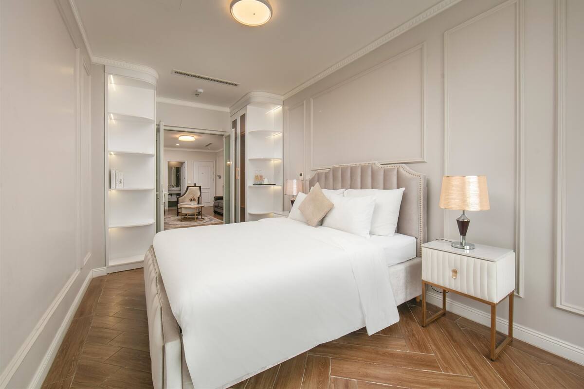 Un dormitorio ordenado con una cama grande, mesitas de noche y una lámpara.