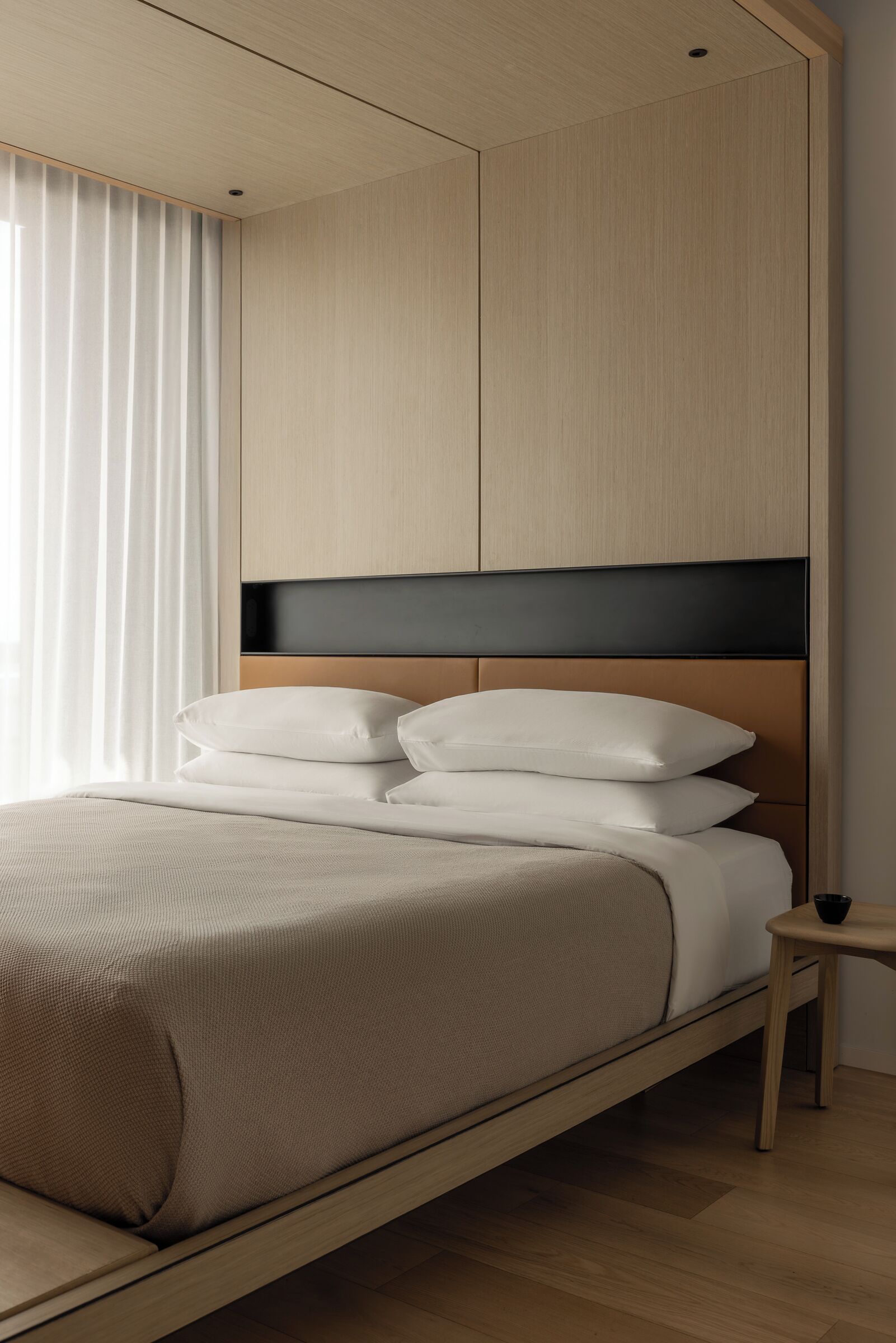 A modern bedroom with a bed, a nightstand, and a headboard.