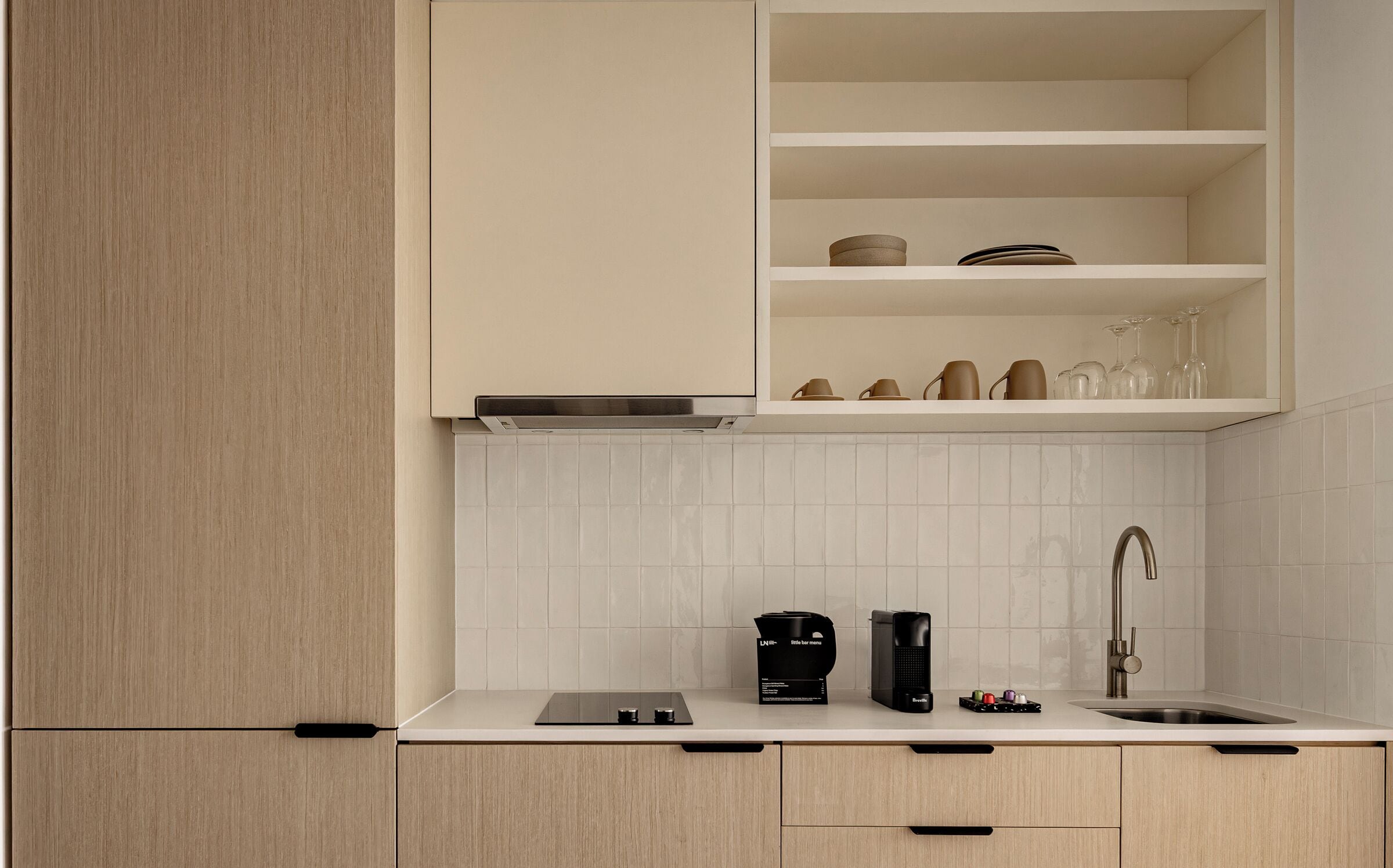 A modern kitchen with white cabinets, a built-in stove, a coffee maker, and a wine glass holder.