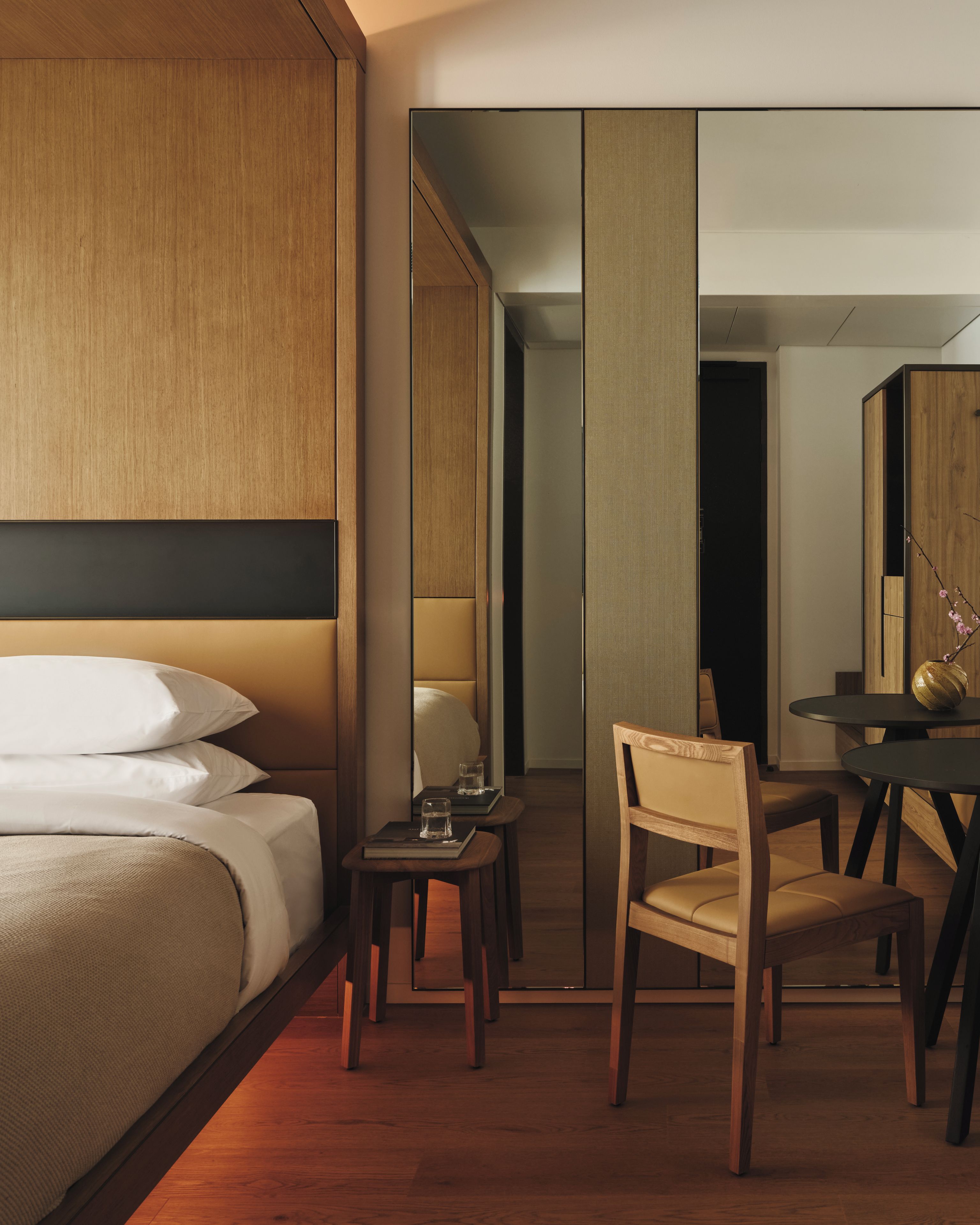 Una habitación de hotel con una cama, un escritorio, una silla y un espejo.
