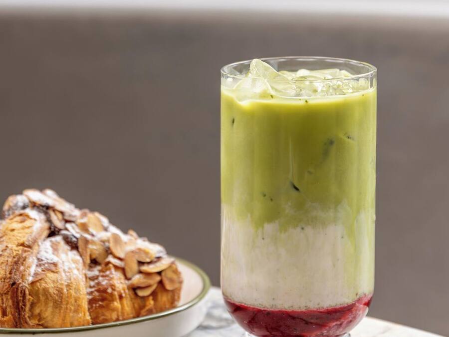 A layered beverage in a glass, a pastry on a plate, and a marble surface.