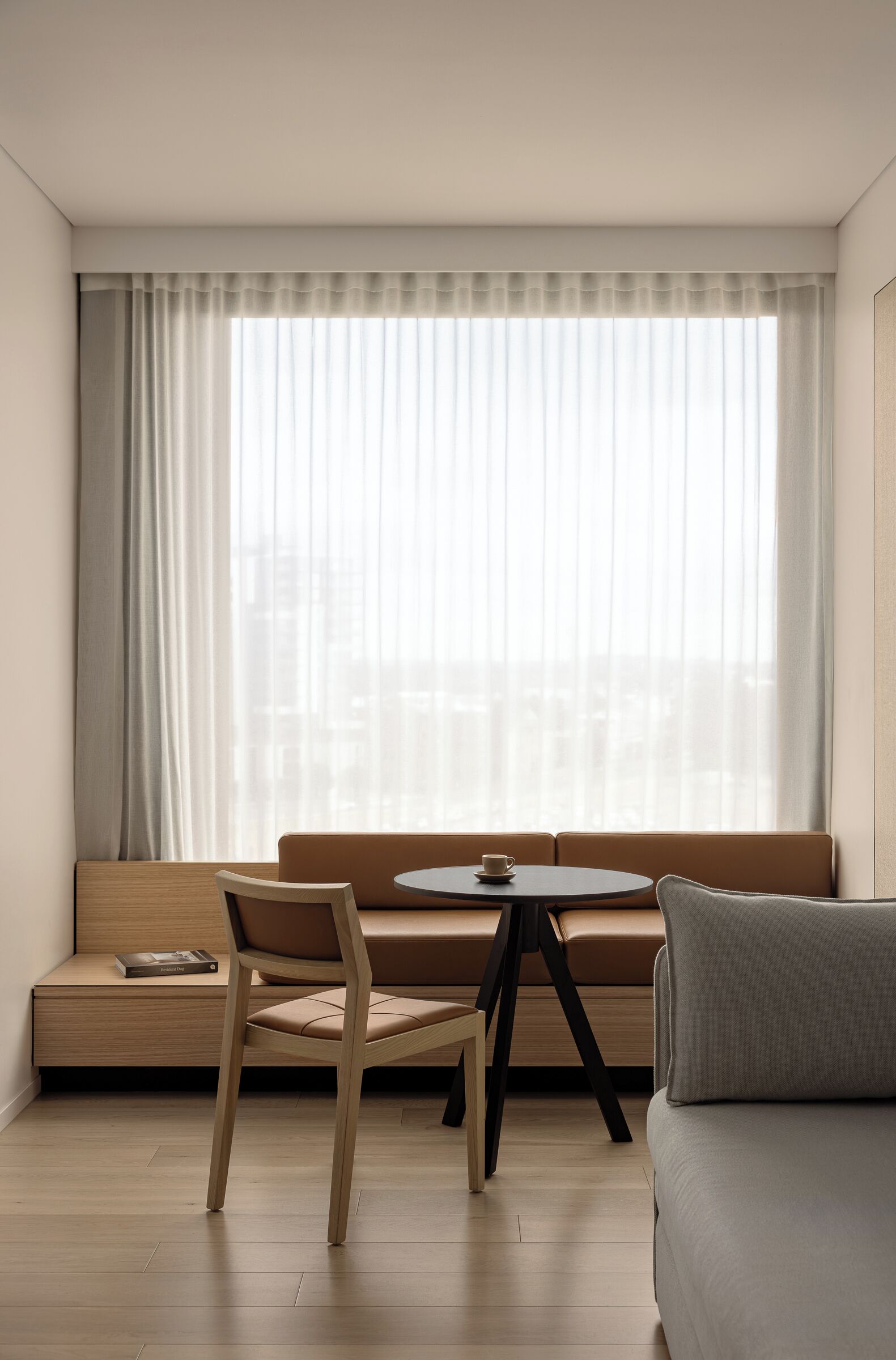A modern room with a wooden bench, a round table with a cup, and a sofa.