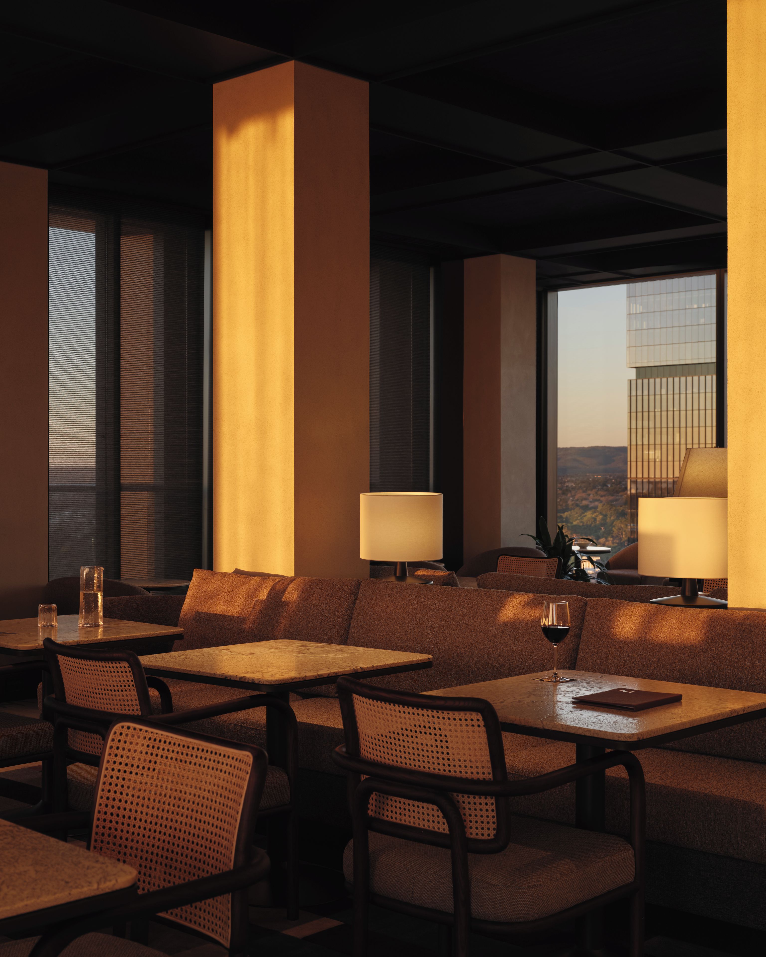 A restaurant interior with high tables and chairs, large windows, and a view of a cityscape.
