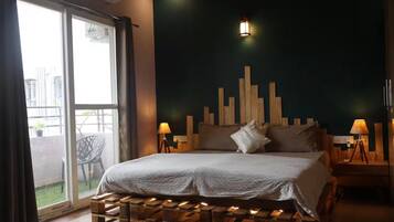 A bedroom with a bed, wooden headboard, two bedside lamps, and a view of the outside through a sliding door.