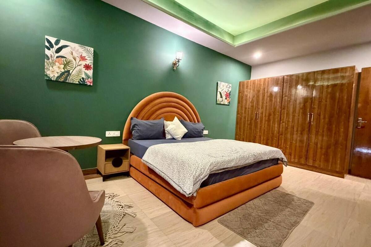 Ein Schlafzimmer mit Bett, Nachttisch, Stuhl, Kleiderschrank und einer Wand mit Kunstwerken.