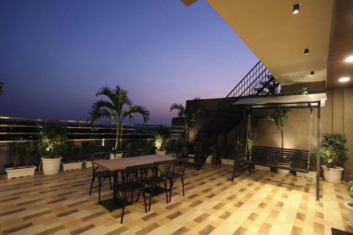 Eine Dachterrasse mit Holzboden, einem Tisch mit Stühlen, Blumentöpfen und einer Treppe, die zu einer höheren Ebene führt.