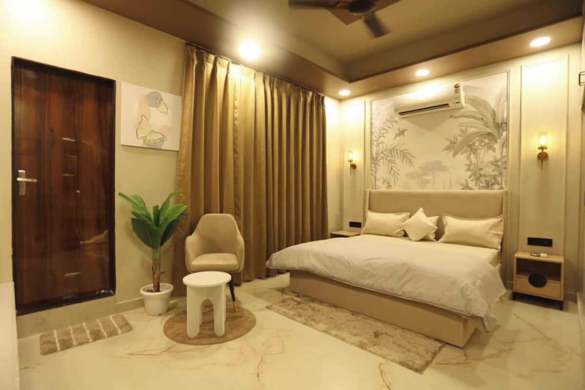 Ein modernes Schlafzimmer mit einem großen Bett, einem Sessel, einem kleinen Tisch und einer Topfpflanze.