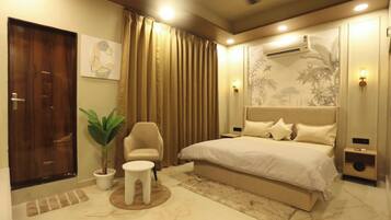 A modern bedroom with a large bed, a chair, a small table, and a potted plant.