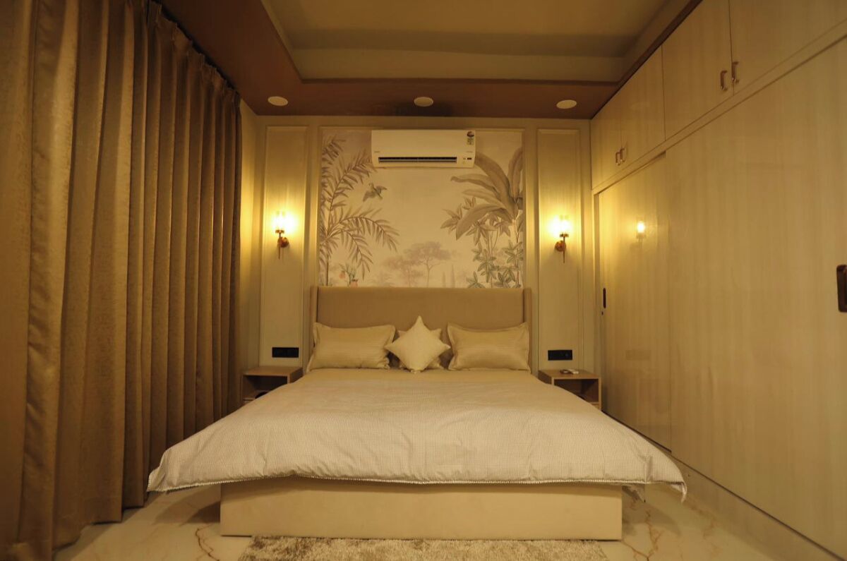 Un dormitorio con una cama grande, dos mesitas de noche, un aire acondicionado de pared y una pared decorativa con follaje.
