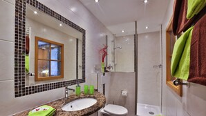 A modern bathroom with a granite countertop sink, a white toilet, a glass-enclosed shower, and a mirror with a wooden frame. - Grünstein - 2-room apartment, south and east-facing balcony, 2 persons, 40 sqm, safe, kitchenette (Ramsau bei Berchtesgaden)