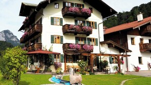 A multi-story building with balconies, outdoor seating, and a sculpture. - Grünstein - 2-room apartment, south and east-facing balcony, 2 persons, 40 sqm, safe, kitchenette (Ramsau bei Berchtesgaden)