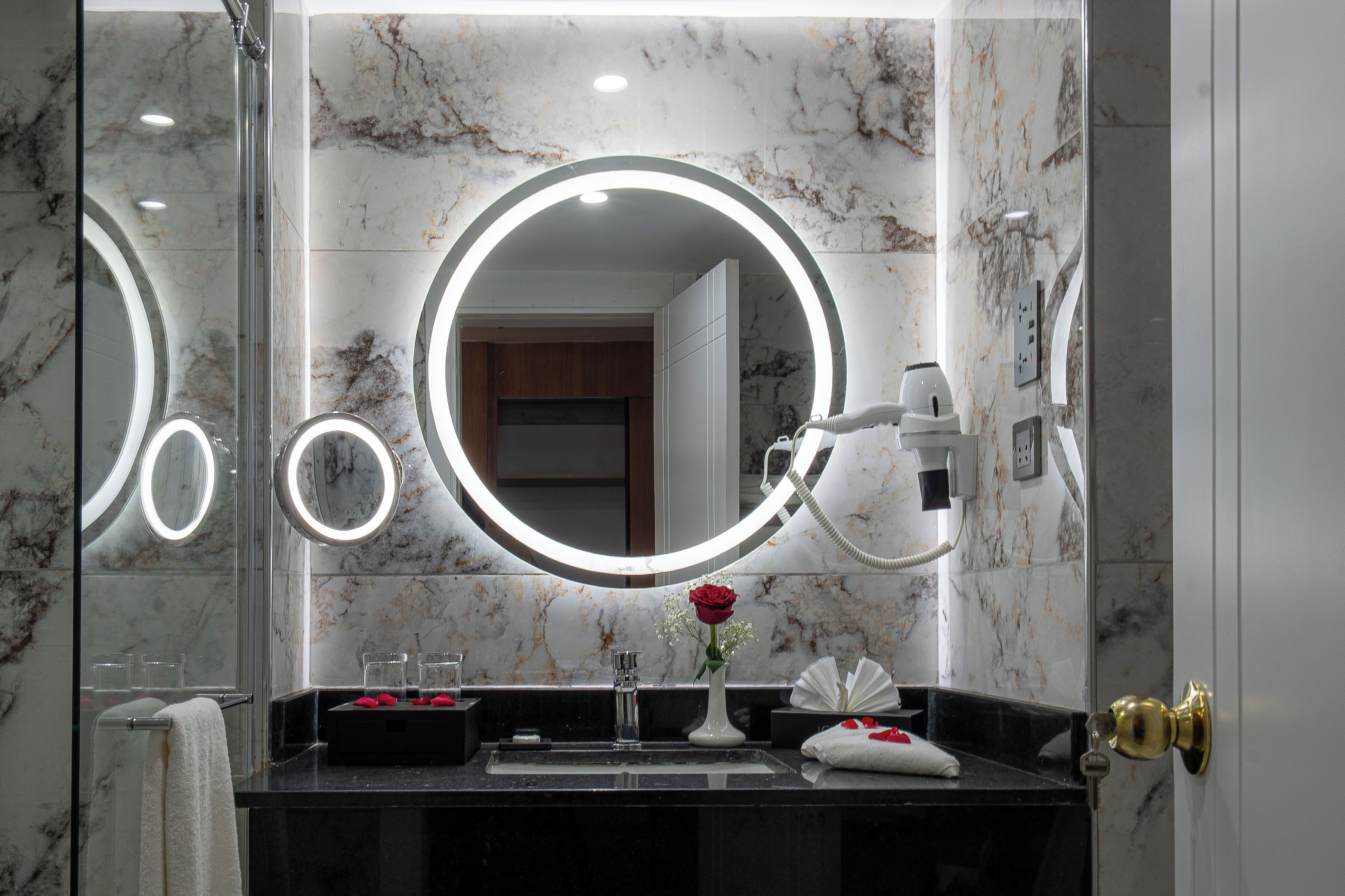 A bathroom with a marble wall, a sink with a mirror, and a towel rack.