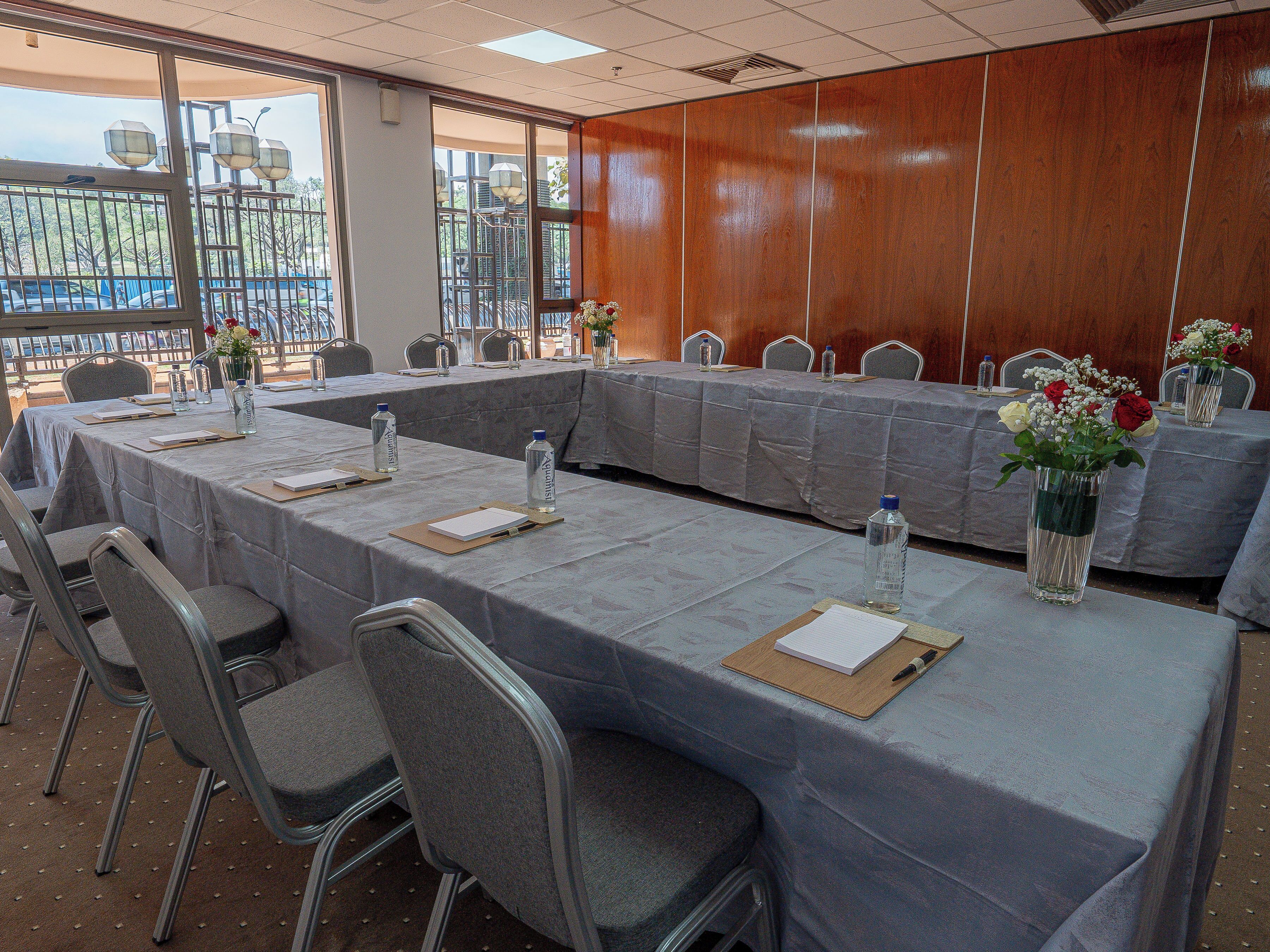 A conference room with a long table, chairs, water bottles, and vases with flowers.