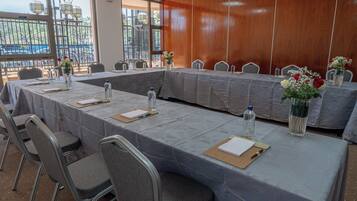 A conference room with a long table, chairs, water bottles, and vases with flowers.