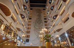 A multi-level atrium with a central spiral staircase, multiple balconies, and a decorative ceiling mural. - Iconic Plaza Hotel (Nairobi)