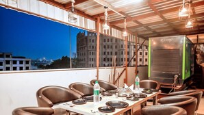 A dining area with a table set for six, chairs, and a view of a cityscape at dusk. - hotel crystal empire  (Dera Bassi)