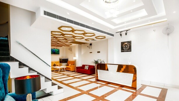 A modern hotel lobby with a geometric floor pattern, a reception desk, a staircase, and a blue armchair. - hotel crystal empire  (Dera Bassi)