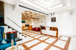 A modern hotel lobby with a geometric floor pattern, a reception desk, a staircase, and a blue armchair. - hotel crystal empire  (Dera Bassi)