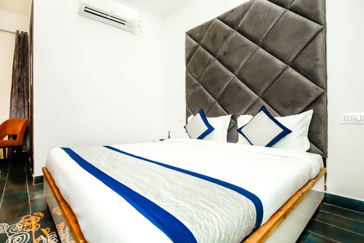 A neatly made bed with a white and blue bedspread, a tufted headboard, and a wooden frame.