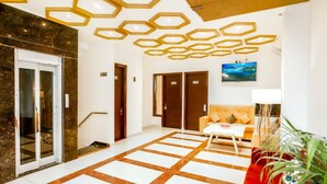 A hotel lobby with a geometric patterned floor, a reception desk, a sofa, and a television mounted on the wall. - hotel crystal empire  (Dera Bassi)