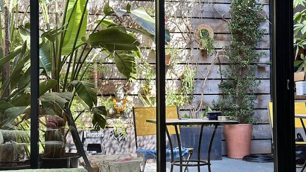 A patio with a table and chairs, surrounded by potted plants and a Buddha statue. - Casa d'Indie - Contemporary charm, well-being and discovery in Perpignan (Perpignan)