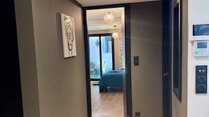 A hallway leading to a bedroom with a bed, a painting on the wall, and a thermostat on the wall. - Casa d'Indie - Contemporary charm, well-being and discovery in Perpignan (Perpignan)
