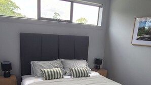 A bedroom with a large bed, two bedside tables, a window, and a framed picture on the wall. - Family Luxury Country Retreat Pool & Spa – Lodge 2 (Yarrambat)