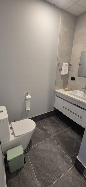Un baño moderno con inodoro, lavamanos y espejo.