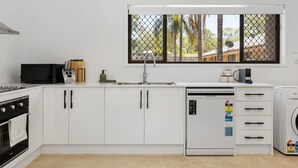 A modern kitchen with white cabinets, a black microwave, a sink, and a dishwasher. - New 2BR GrannyFlat,Near Movie World, Wet'Wild,Pool (Helensvale)
