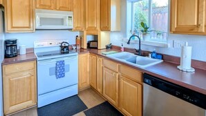 A kitchen with wooden cabinets, a white stove, a microwave, a sink, and a dishwasher. - Entire home in Folsom, California (Folsom)