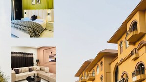 Cet hôtel présente un intérieur moderne, avec un lit recouvert d’une couvre-lit à motifs, un canapé agrémenté de coussins et une petite table sur laquelle se trouve une lampe. L’extérieur se caractérise par un bâtiment jaune doté de balcons, donnant sur la rue.