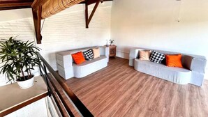 A spacious living area with two grey sofas, wooden flooring, and a ceiling fan. - Villa Loba (Denpasar)