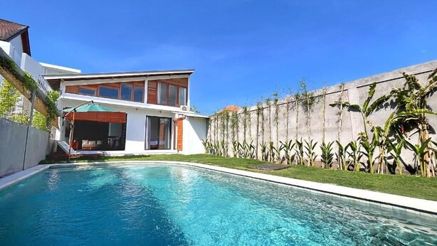 A modern house with a swimming pool, a covered patio, and a garden with tropical plants. - Villa Loba (Denpasar)