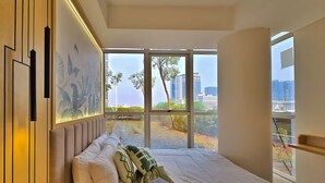 Een moderne slaapkamer met een groot raam, een bed met wit beddengoed en een groene plaid.