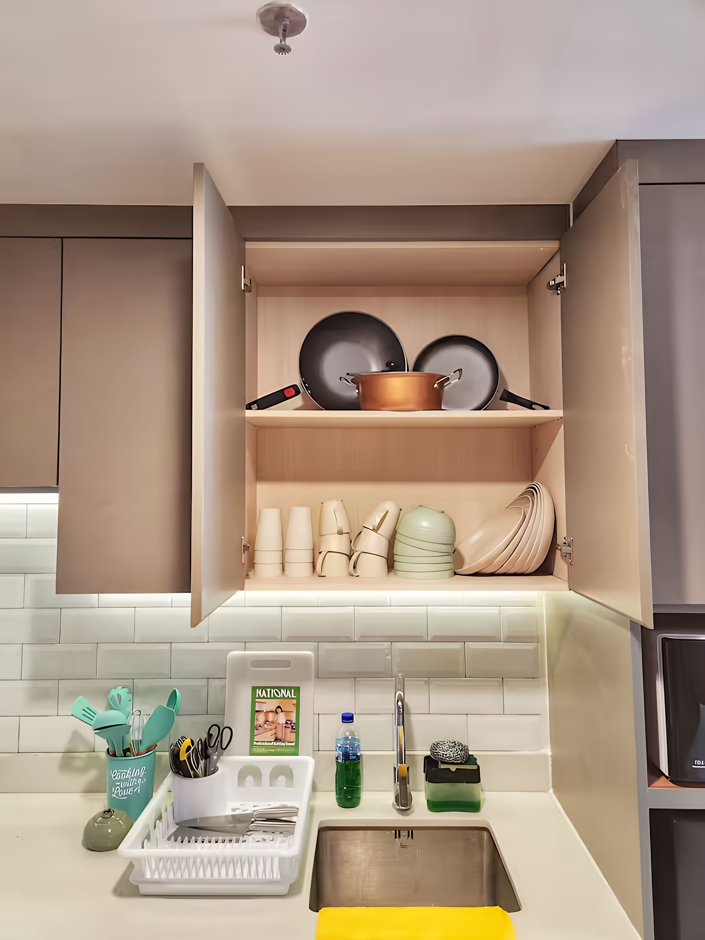 A kitchen with a built-in shelf holding cookware, a sink, and various kitchen utensils.