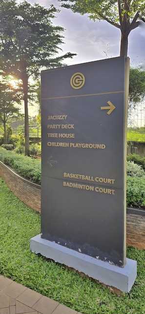 Een richtingwijzer met pijlen die naar verschillende voorzieningen wijzen, zoals een basketbalveld en een badmintonbaan.