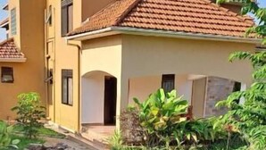 A two-story house with a tiled roof, a small front porch, and a well-maintained lawn. - Banks Boutique Inn Kampala (Kampala)