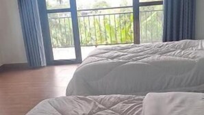 A bedroom with a bed, a window with curtains, and a view of greenery outside. - Banks Boutique Inn Kampala (Kampala)