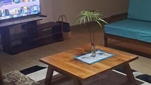 A living room with a wooden coffee table, a television, and a blue sofa. - Banks Boutique Inn Kampala (Kampala)