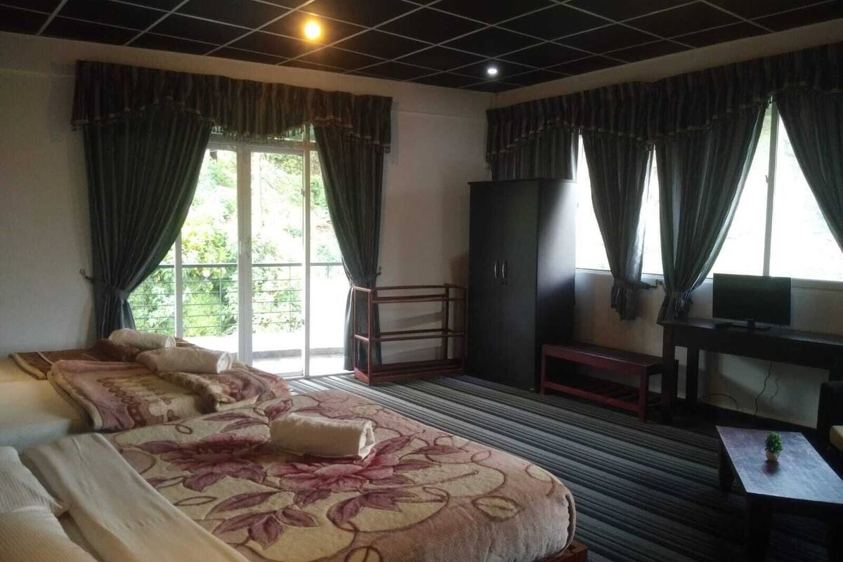 A hotel room with a bed, a desk, a television, and a balcony.