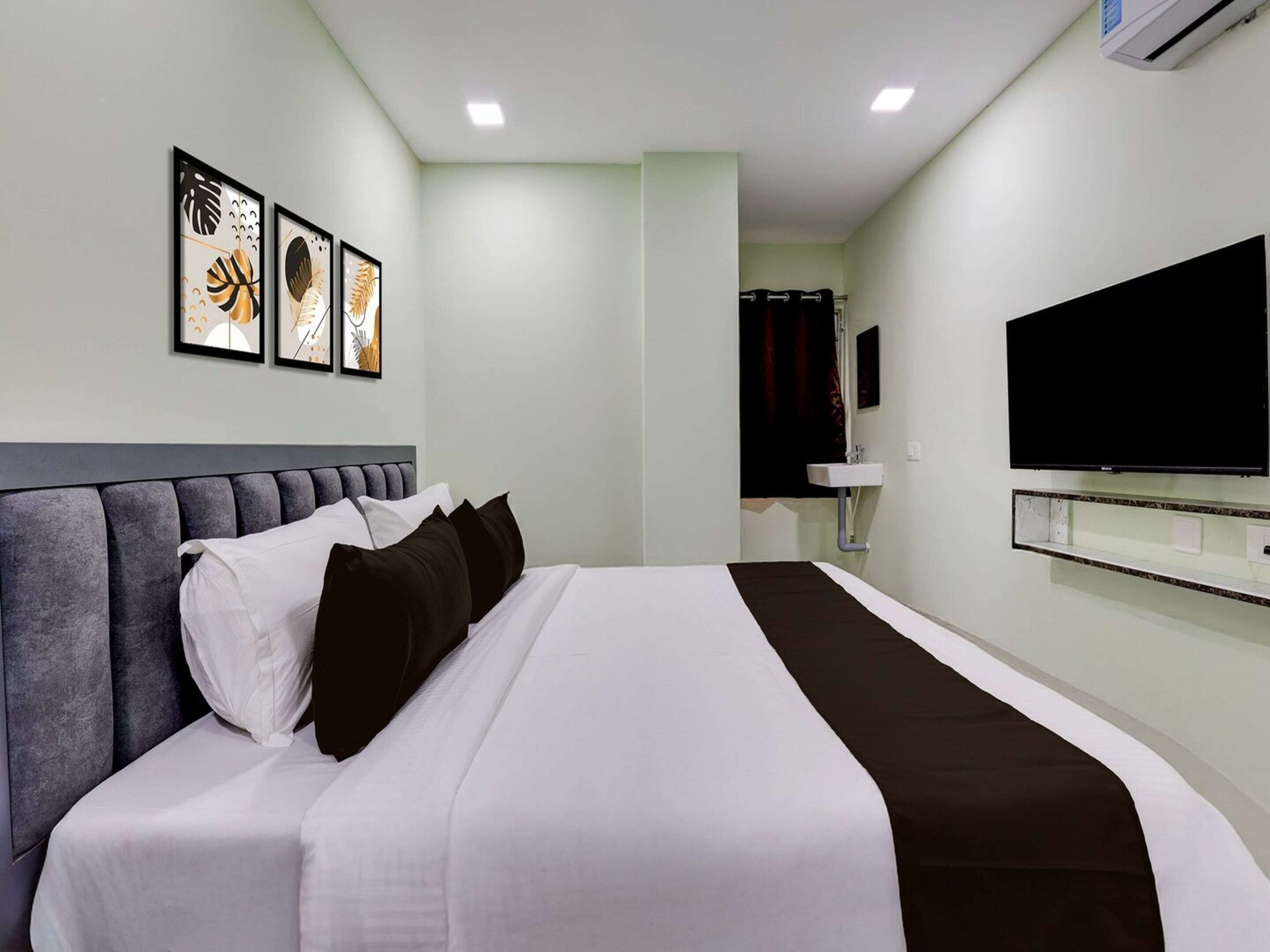 Una camera d'albergo con un letto, una televisione, un lavandino e quadri appesi al muro.