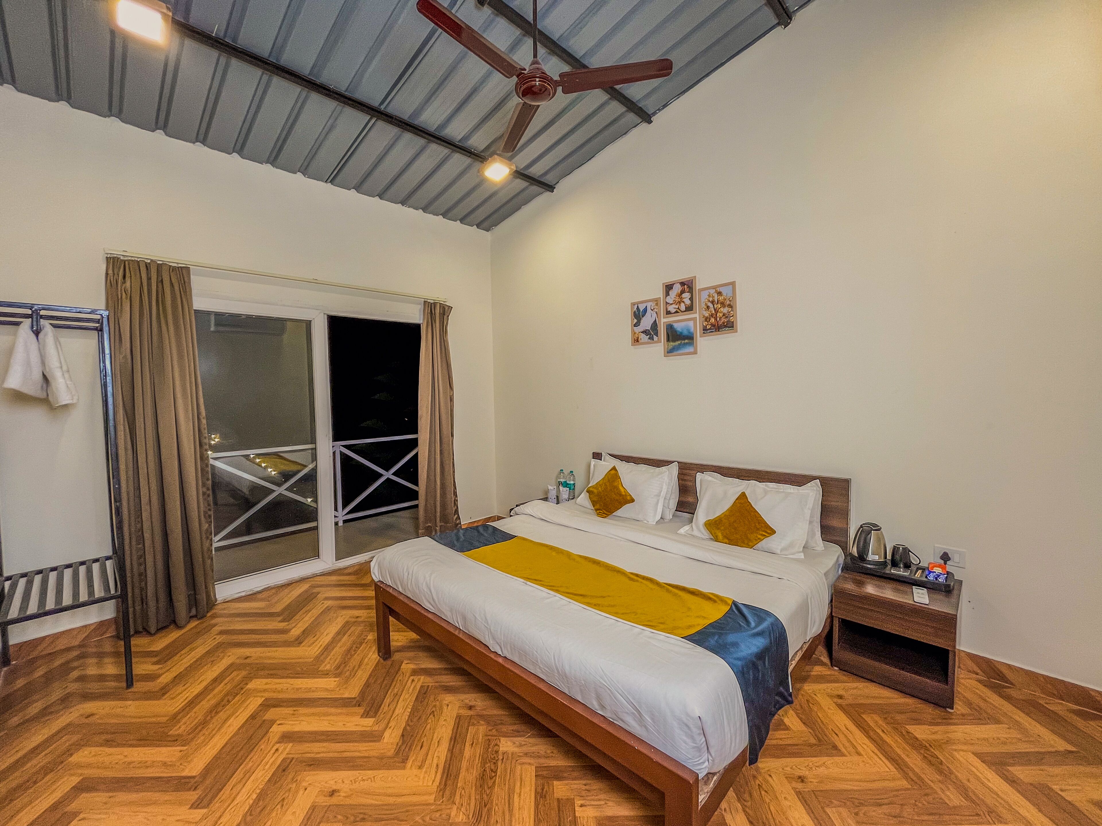 Una camera da letto con un letto, un comodino, una ventola a soffitto e una porta scorrevole in vetro che dà su un balcone.